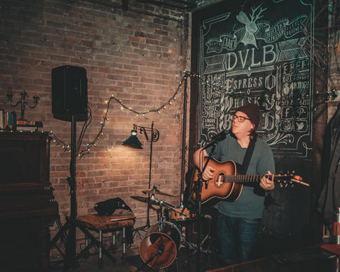 Richard Garvey, man singing and playing guitar, exposed brick wall, writing on the chalk wall, Death Valley's Little Brother as the venue