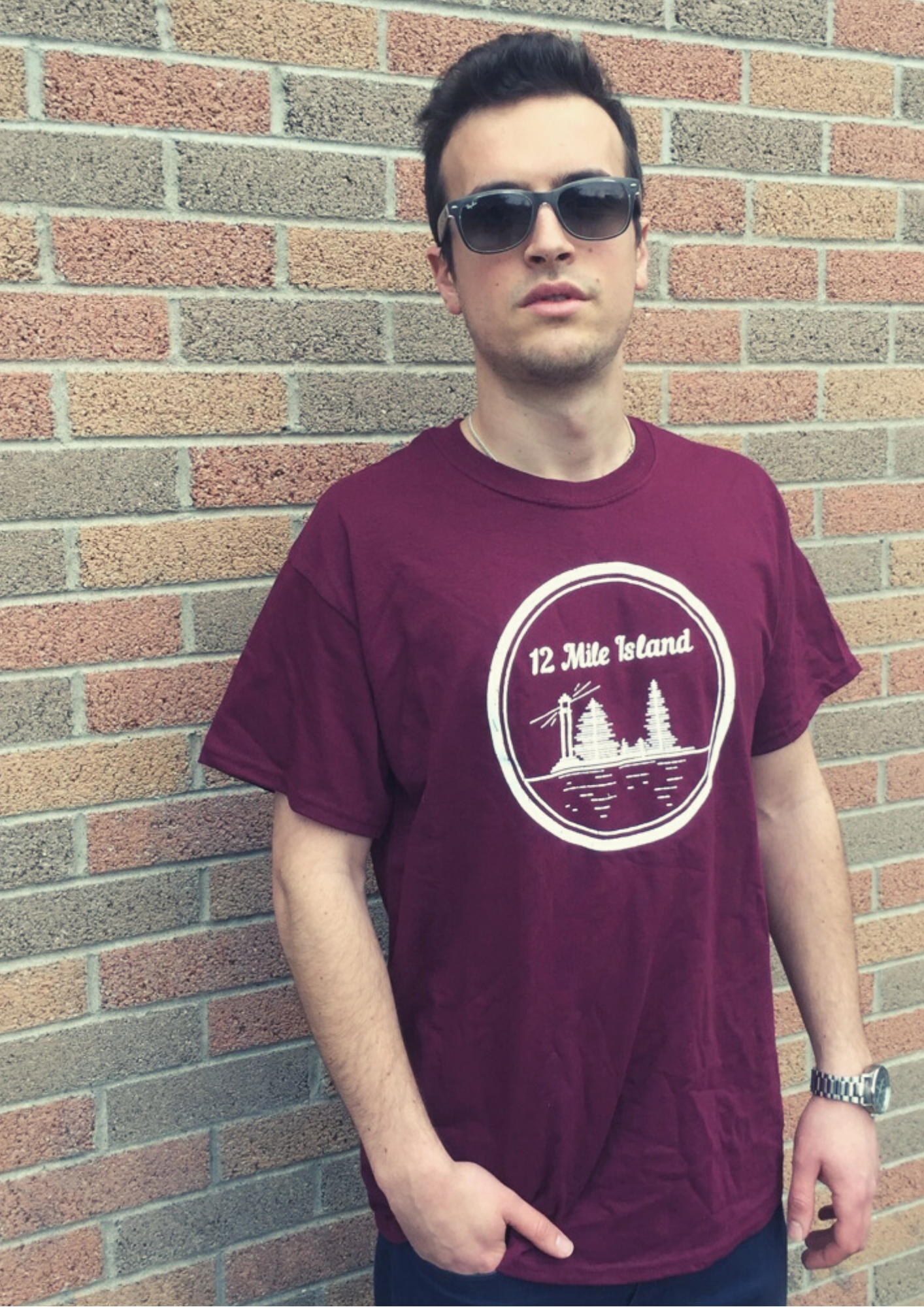 guy with sunglasses wearing a burgundy shirt, '12 Mile Island' printed on the shirt