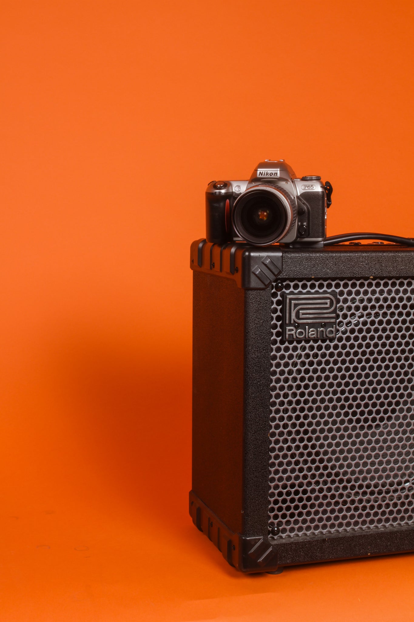 camera sitting on top of a speaker with an orange back ground