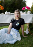 a girl sitting in the grass with a black limited run t-shirt