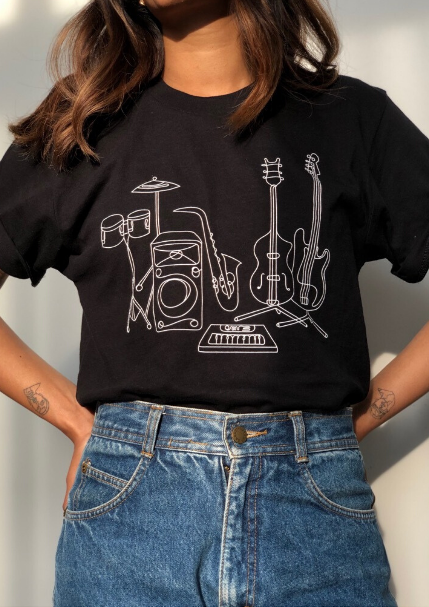 a person wearing a black t-shirt with a graphic white outline of different instruments
